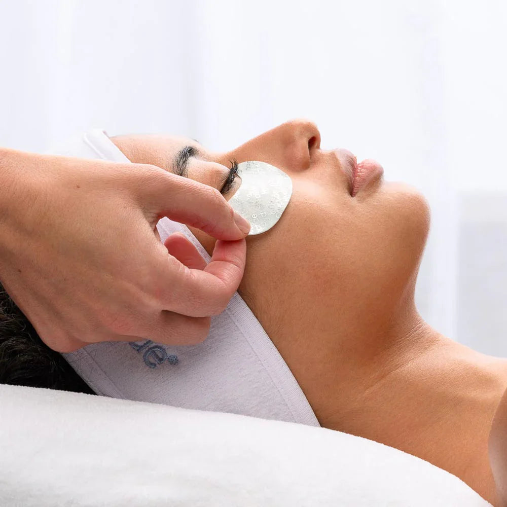 Person receiving Hydropeptide Polypeptide eye treatment with patches on a white background