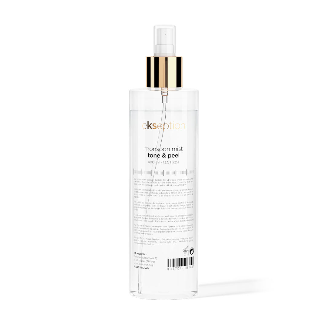 A clear bottle of Ekspection Monsoon Mist Tone & Peel exfoliating mist with a gold collar and clear spray nozzle, shown on a white background with a soft shadow.