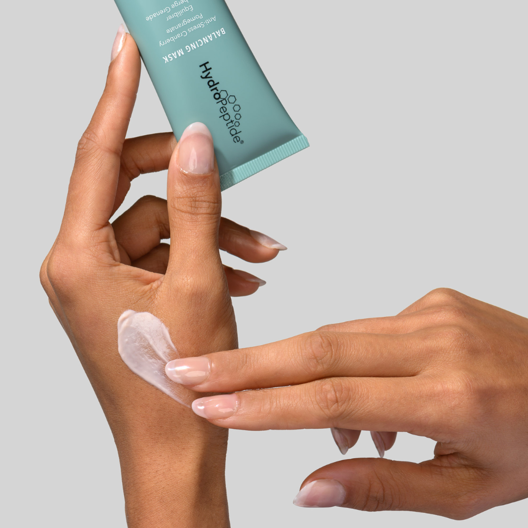 Person applying Hydropeptide skincare product to wrist with a gray background