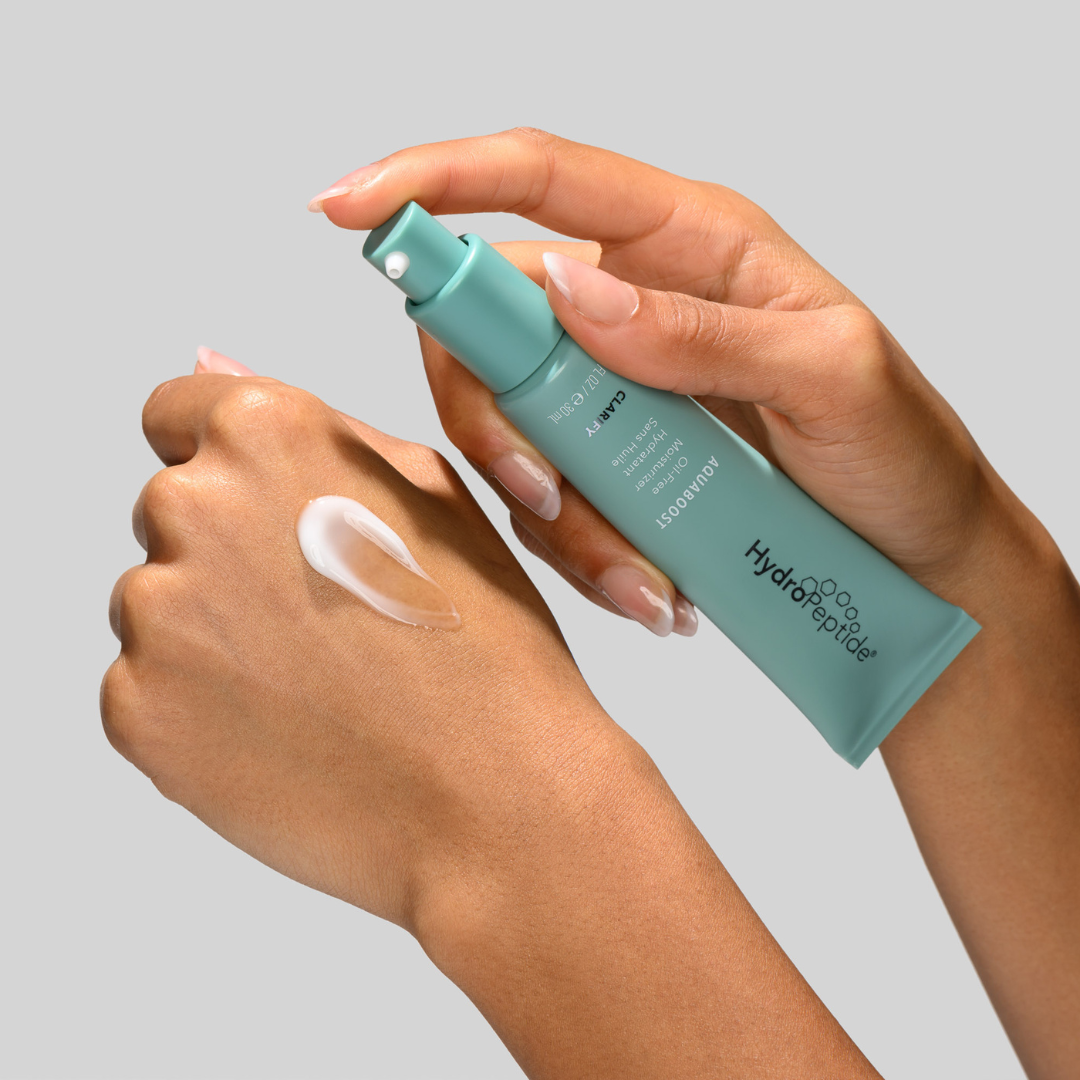 Hand holding Hydropeptide Aquaboost with another hand applying cream on a gray background