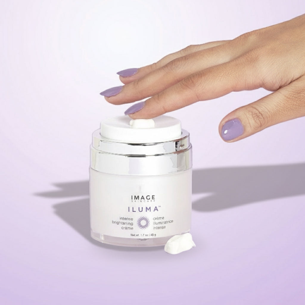 Hand holding a jar of Image Skincare Iluma cream against a light purple background