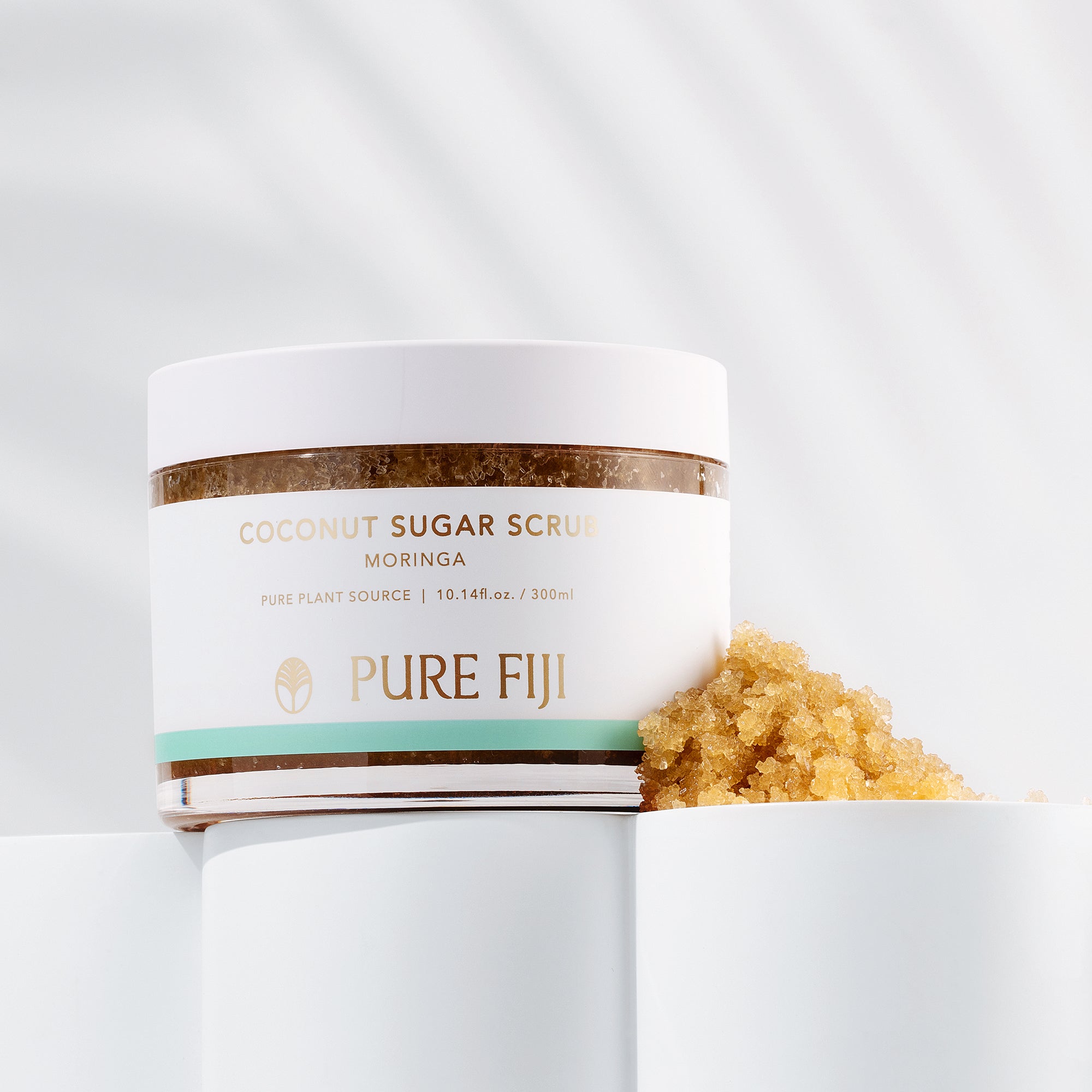 Jar of Pure Fiji coconut sugar scrub with visible scrub on a white background