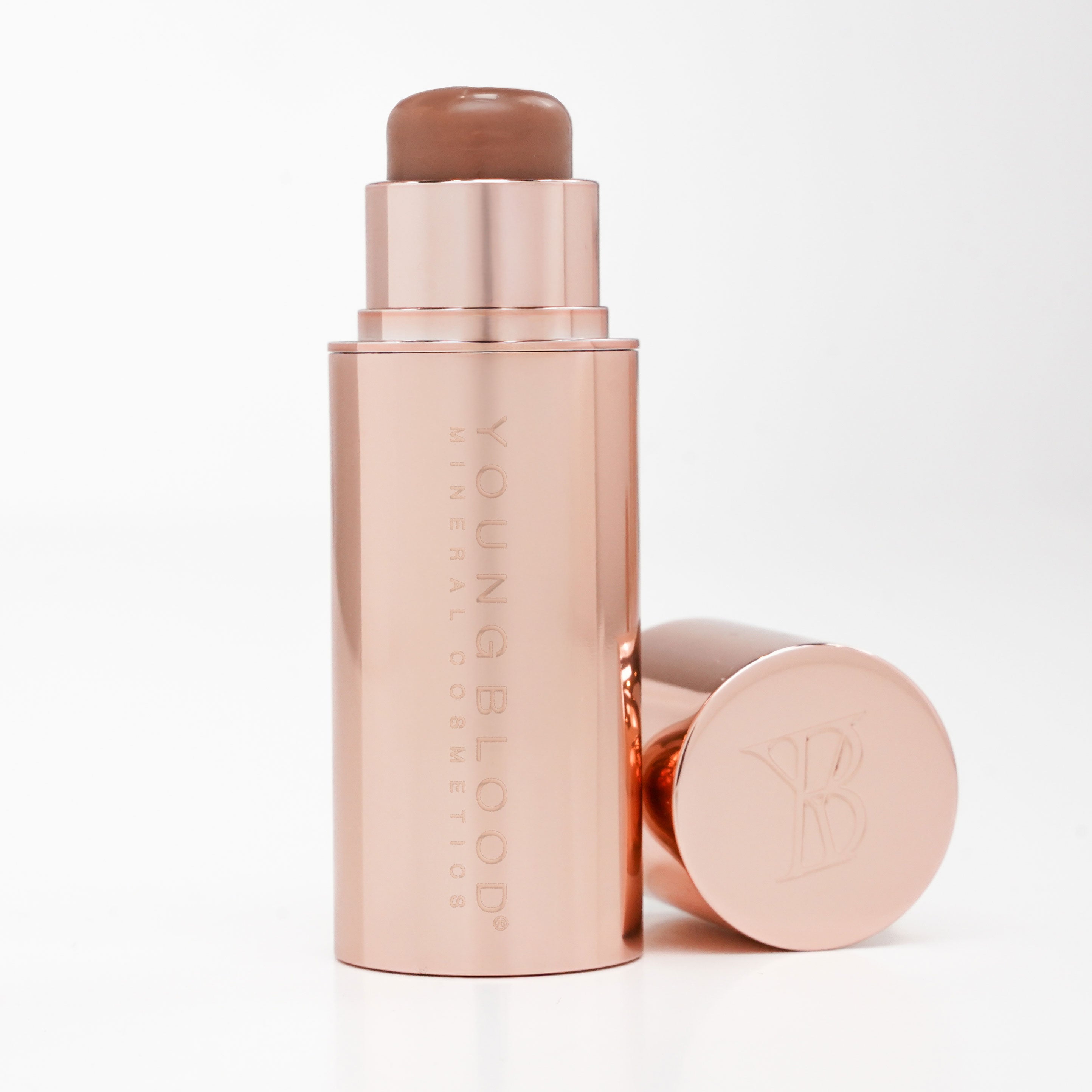 Rose gold Youngblood makeup stick with brown shade on a white background