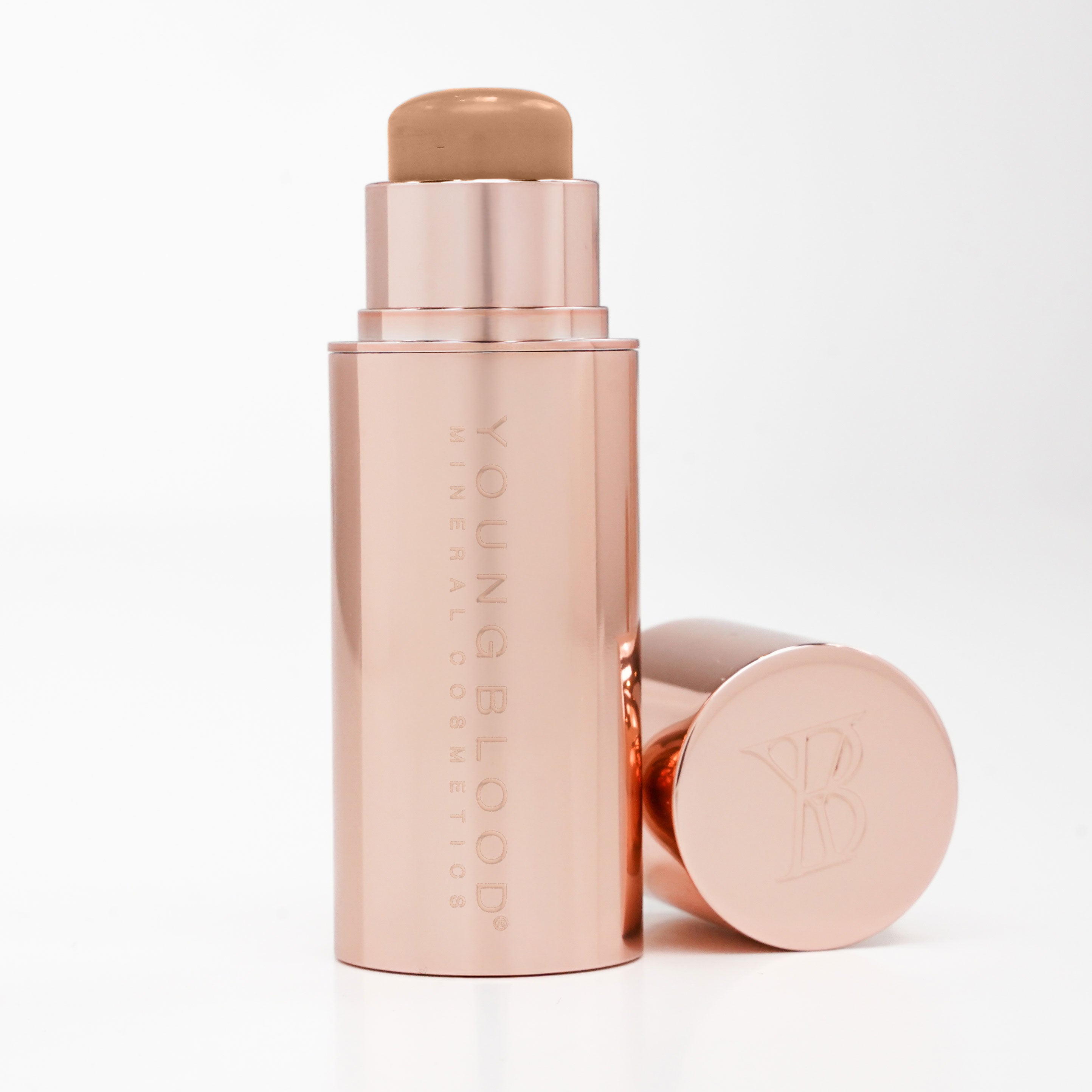 Rose gold Youngblood makeup stick with cap on a white background