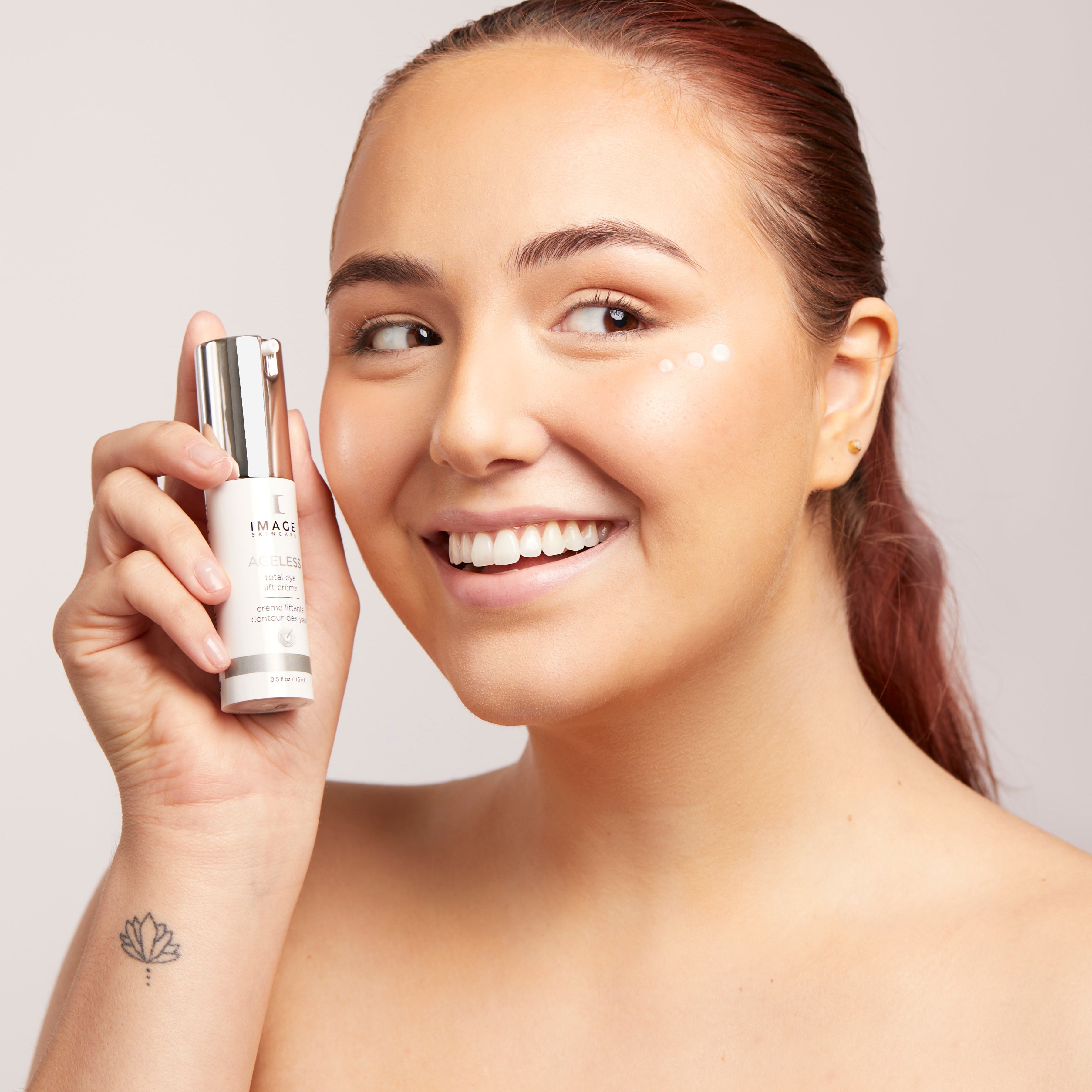 Woman applying skincare product to her face with a neutral background