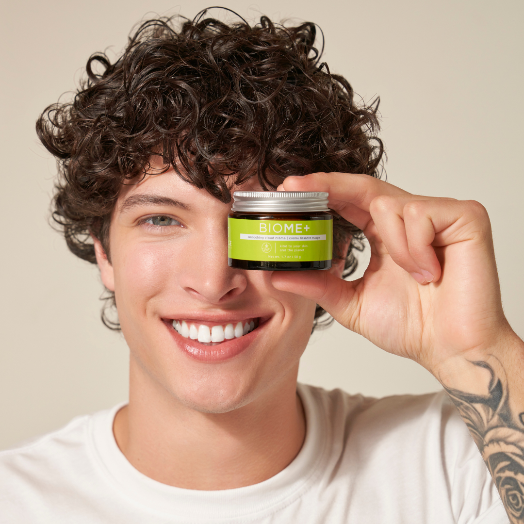 Person holding a Biome+ product jar near their face against a neutral background