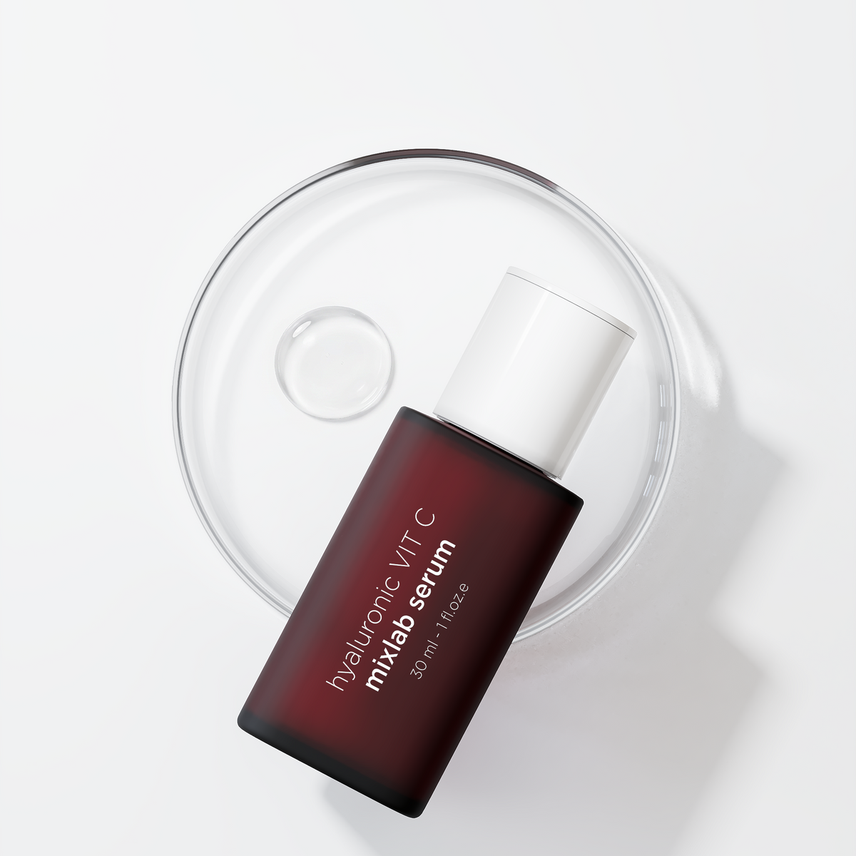 A dark red rectangular bottle of mixlab serum with a white cap, resting on a clear glass dish against a clean white background.