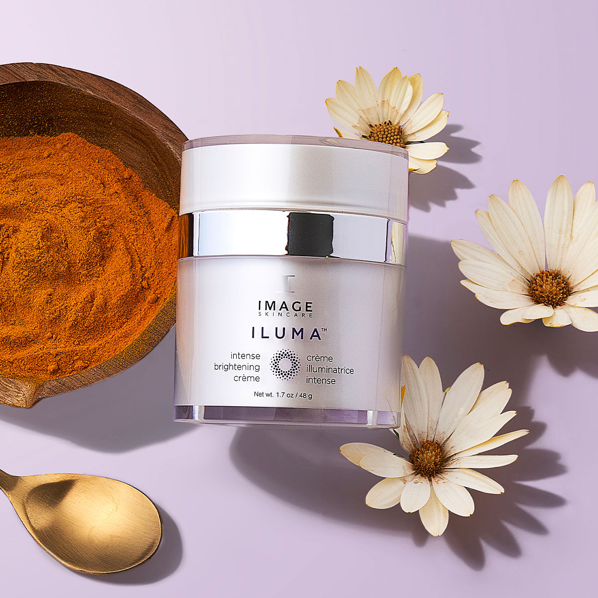 Image of a skincare product with turmeric powder, a spoon, and flowers on a light purple background
