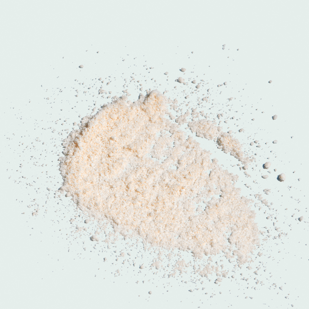 Heart-shaped pile of light brown powder on a light gray background