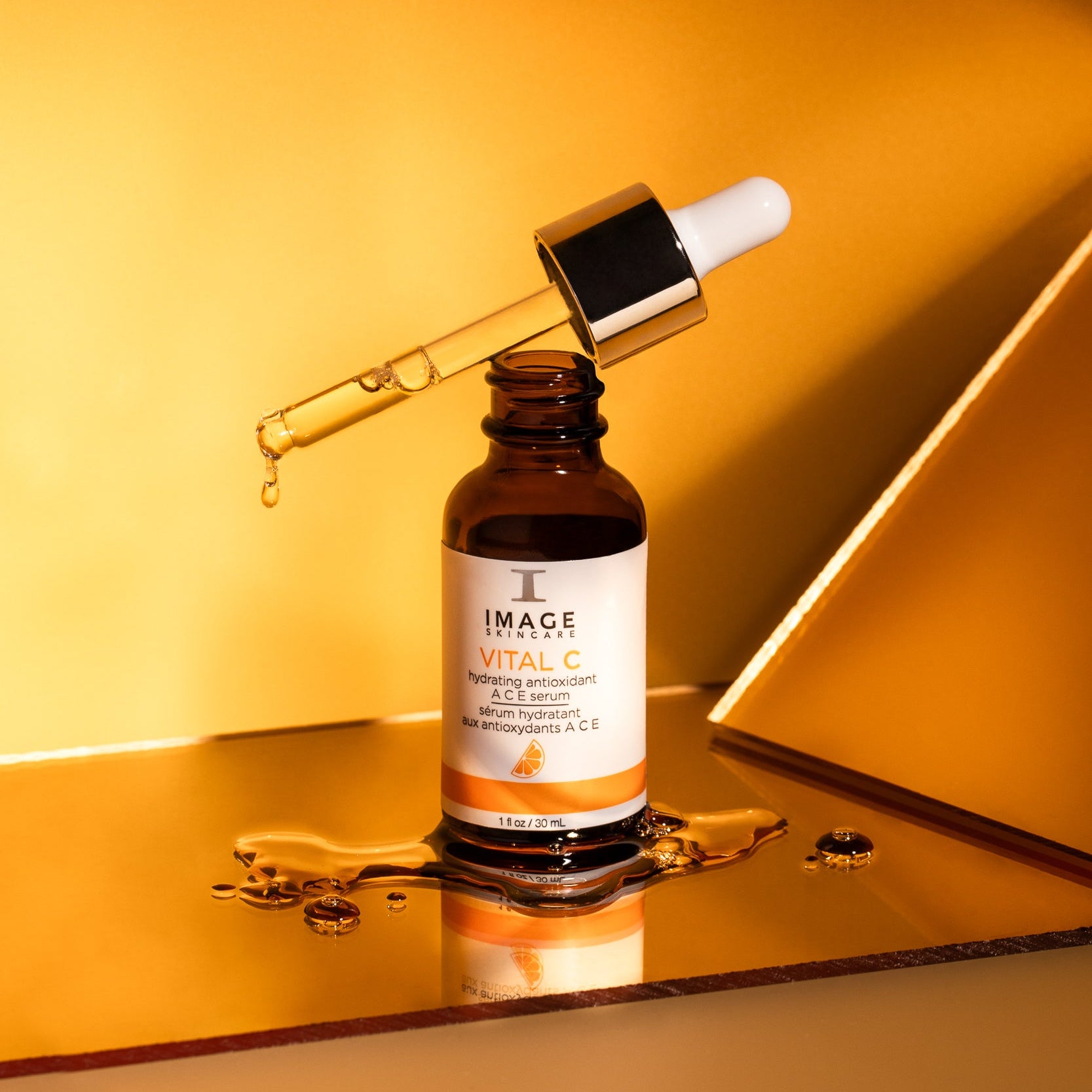 Bottle of IMAGE Skincare Vital C serum with a dropper on a reflective surface.