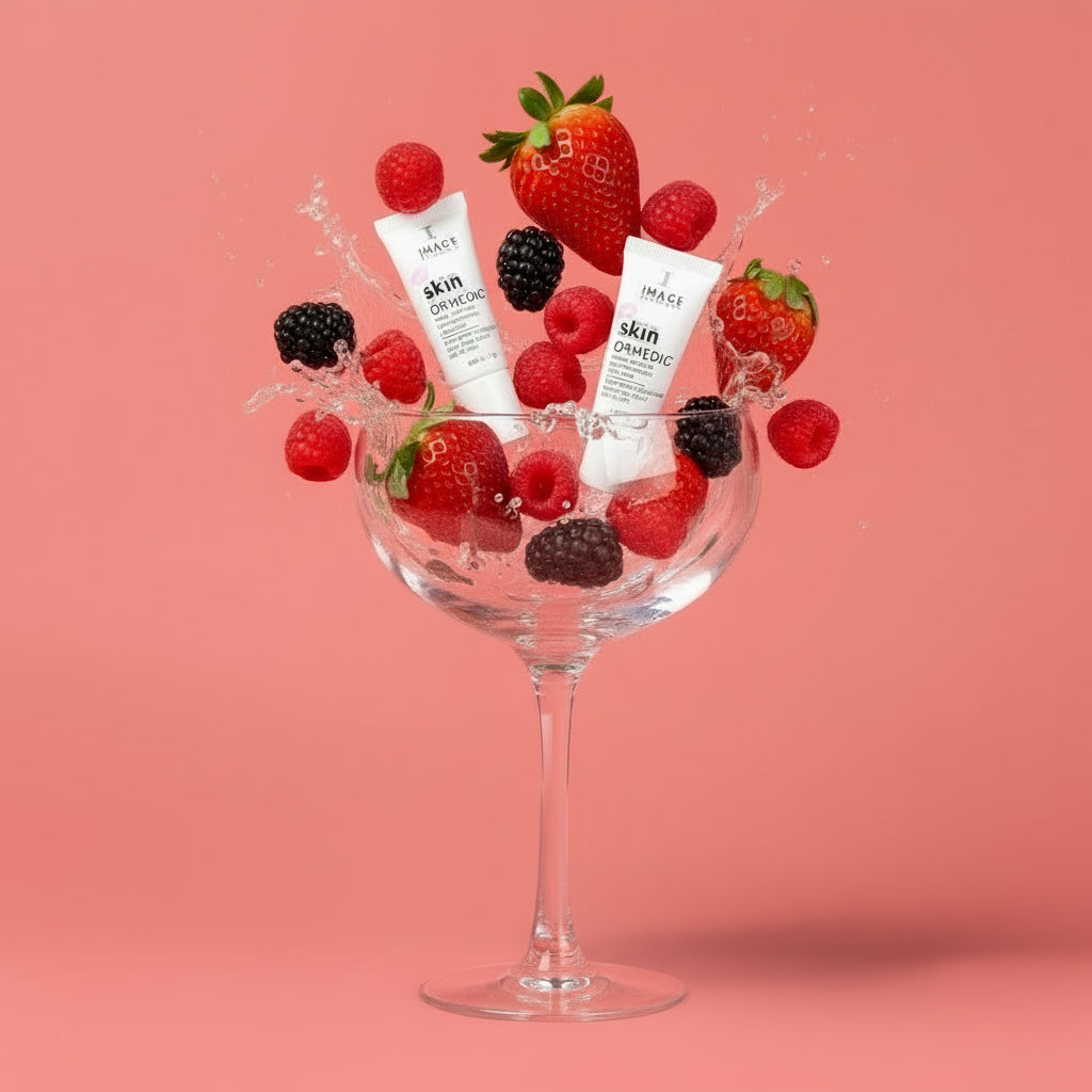 Two skincare bottles surrounded by strawberries and blackberries on a pink background