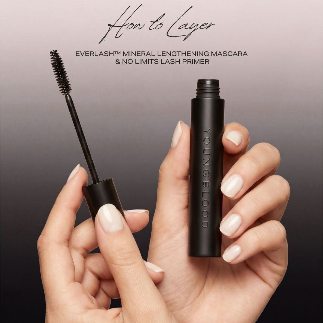 A hand holds an open tube of Youngblood EverLash Mineral Lengthening Mascara and applicator wand against a dark gradient background with text reading 'How to Layer'.