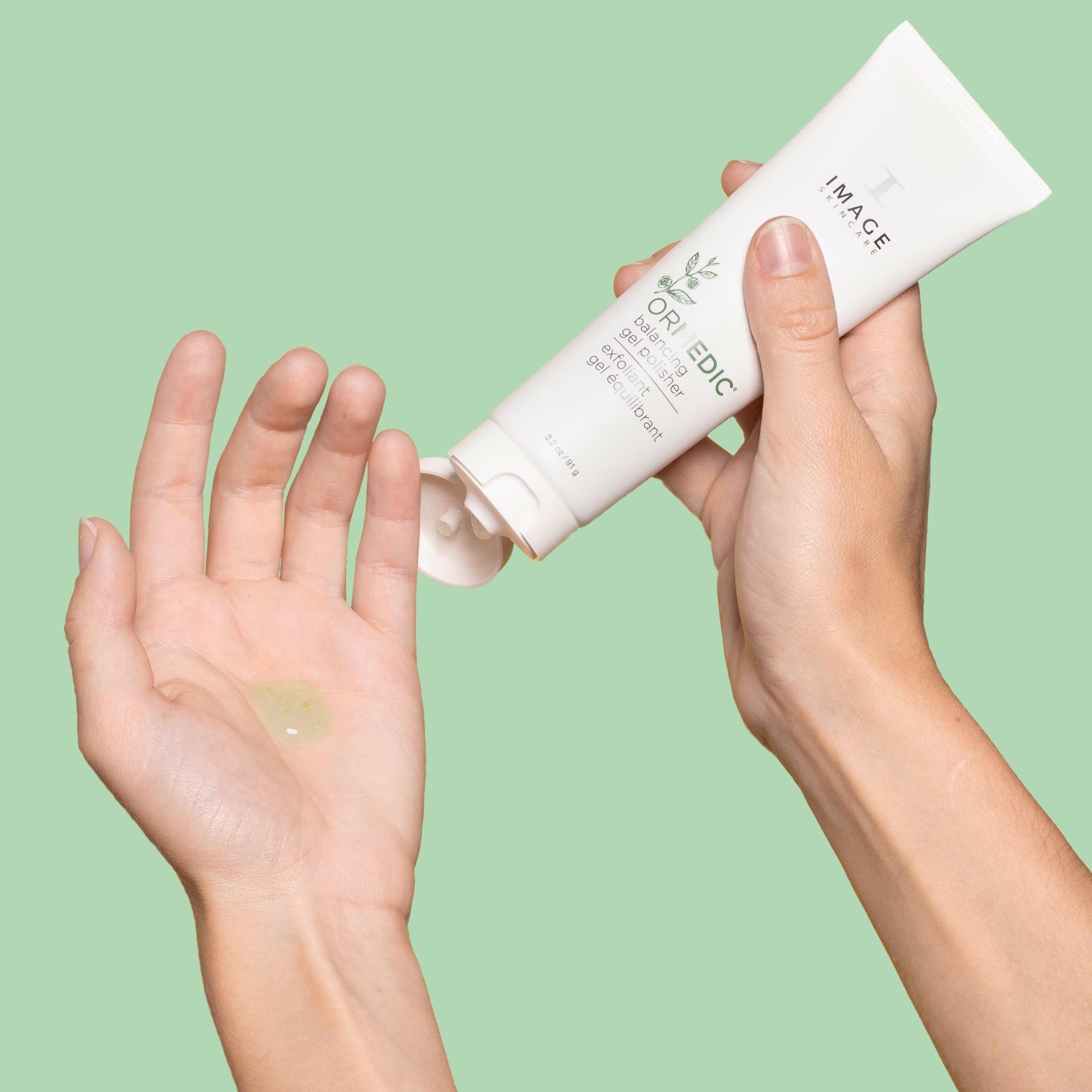 Person applying skincare product to hands with a green background