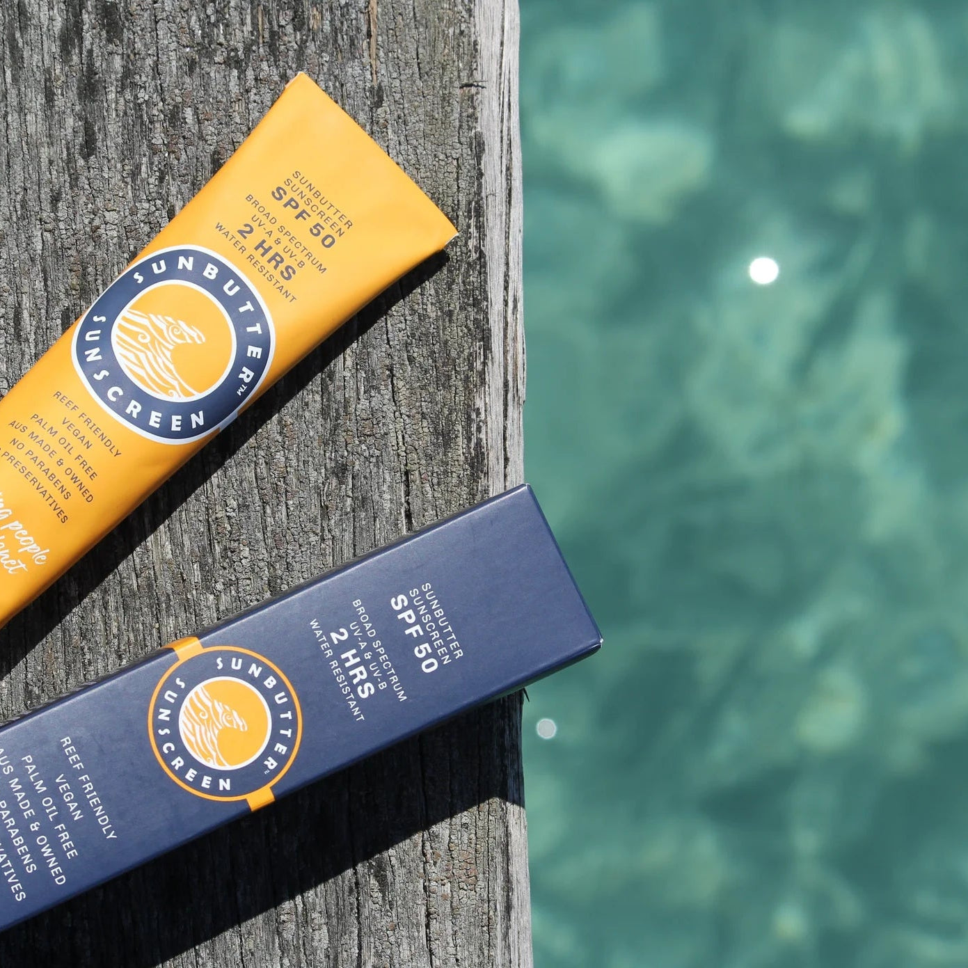 Two tubes of SunButter sunscreen on a wooden post with water in the background