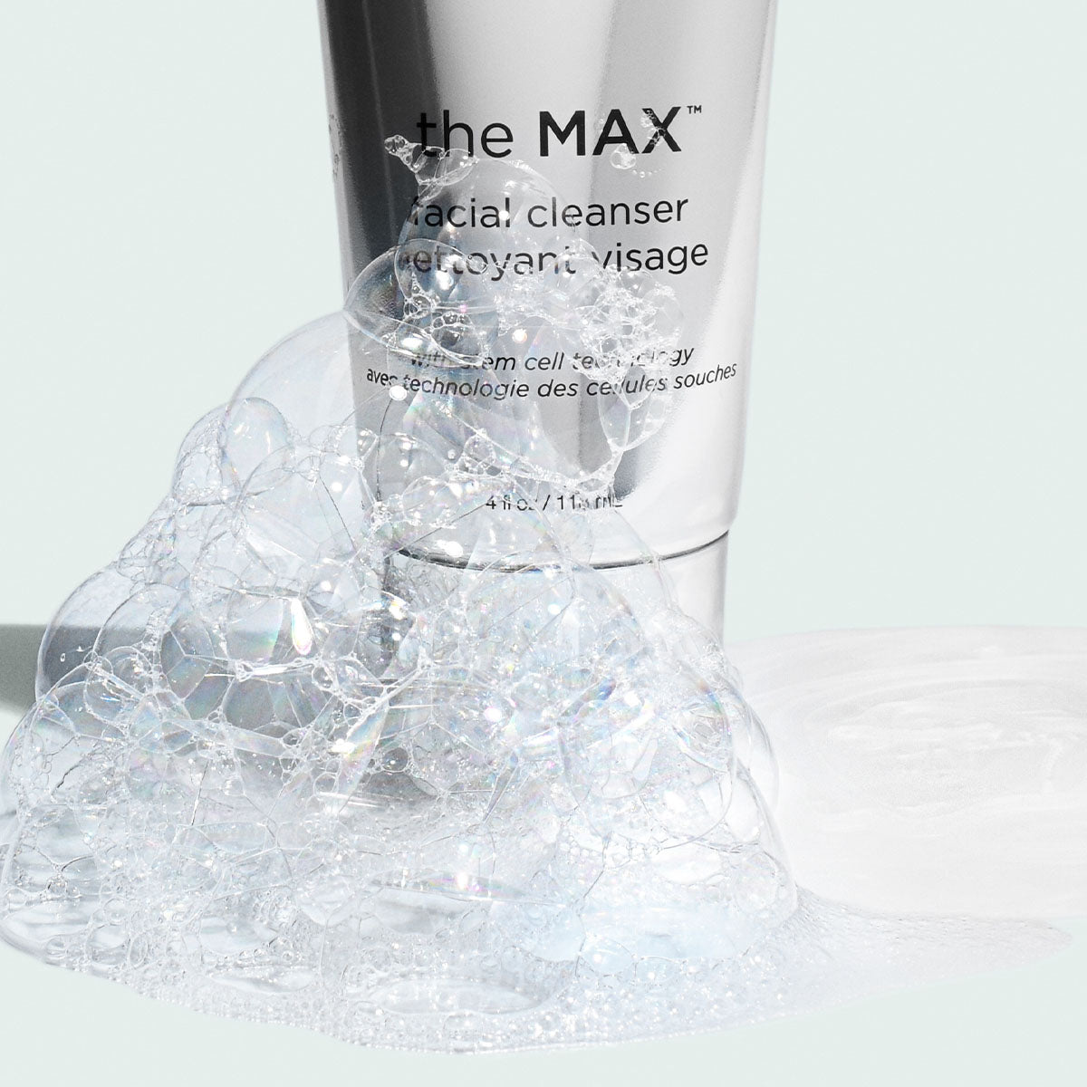 Facial cleanser bottle with foam on a light background