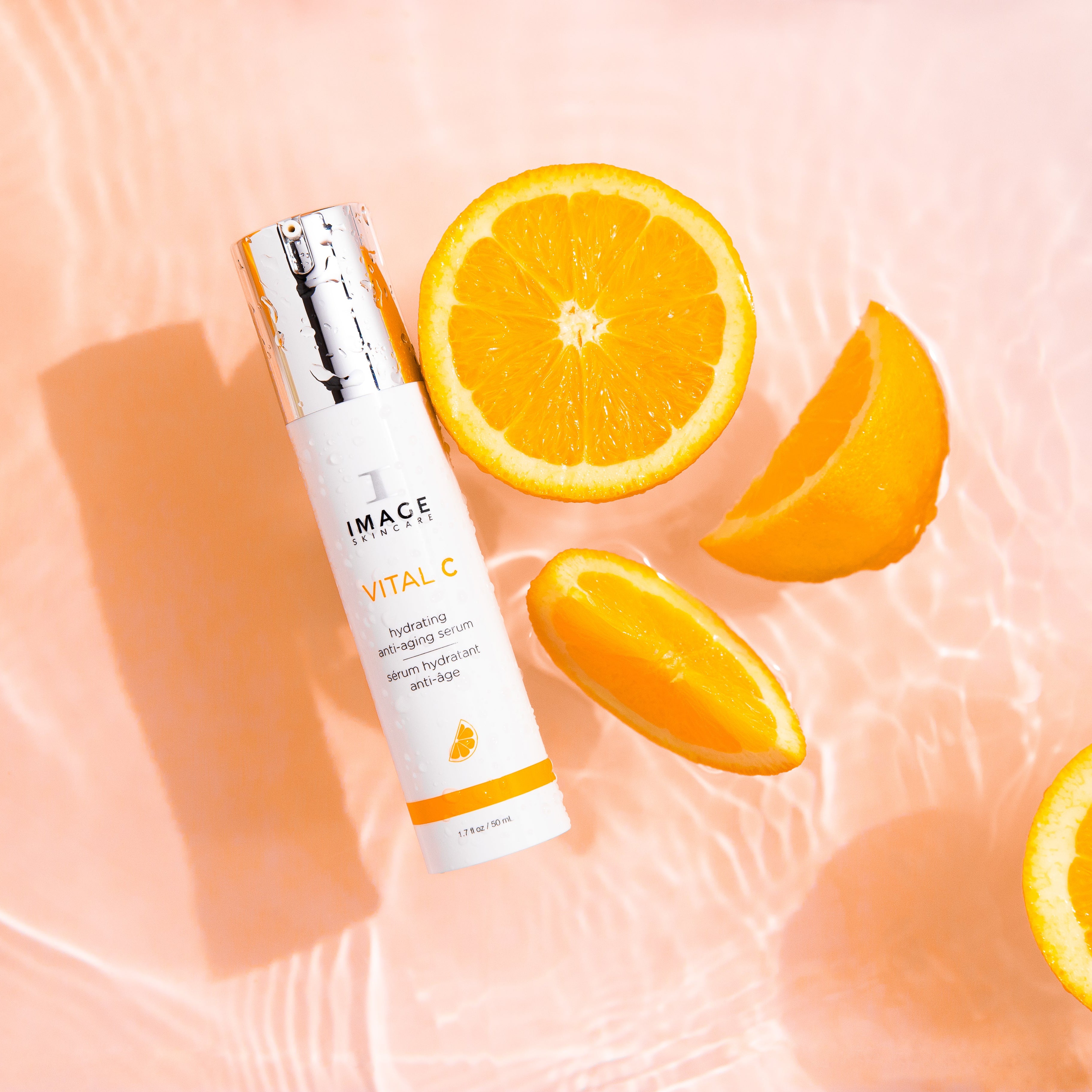 IMAC Skincare bottle with sliced oranges on a pink background