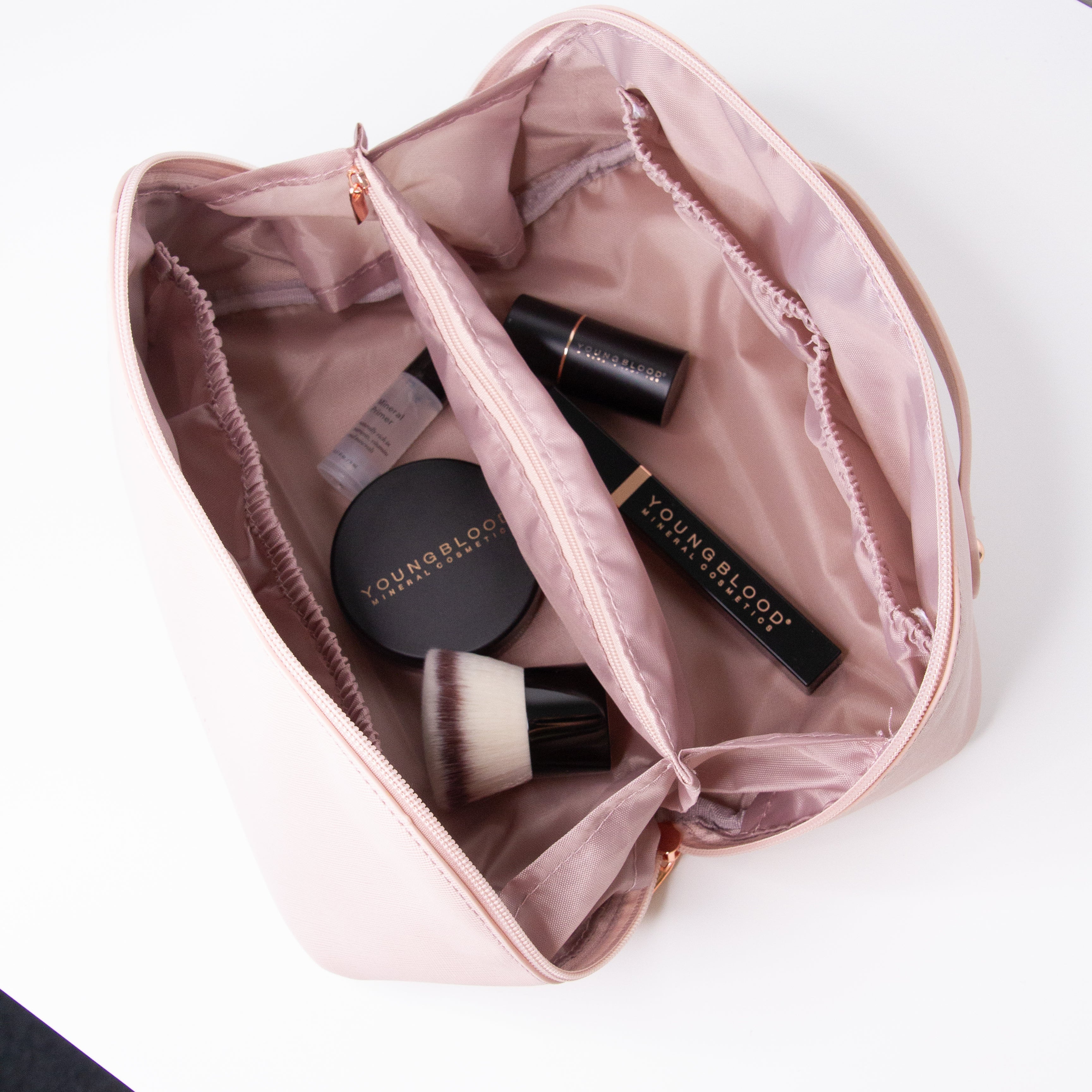 Pink makeup bag with Youngblood products on a white background
