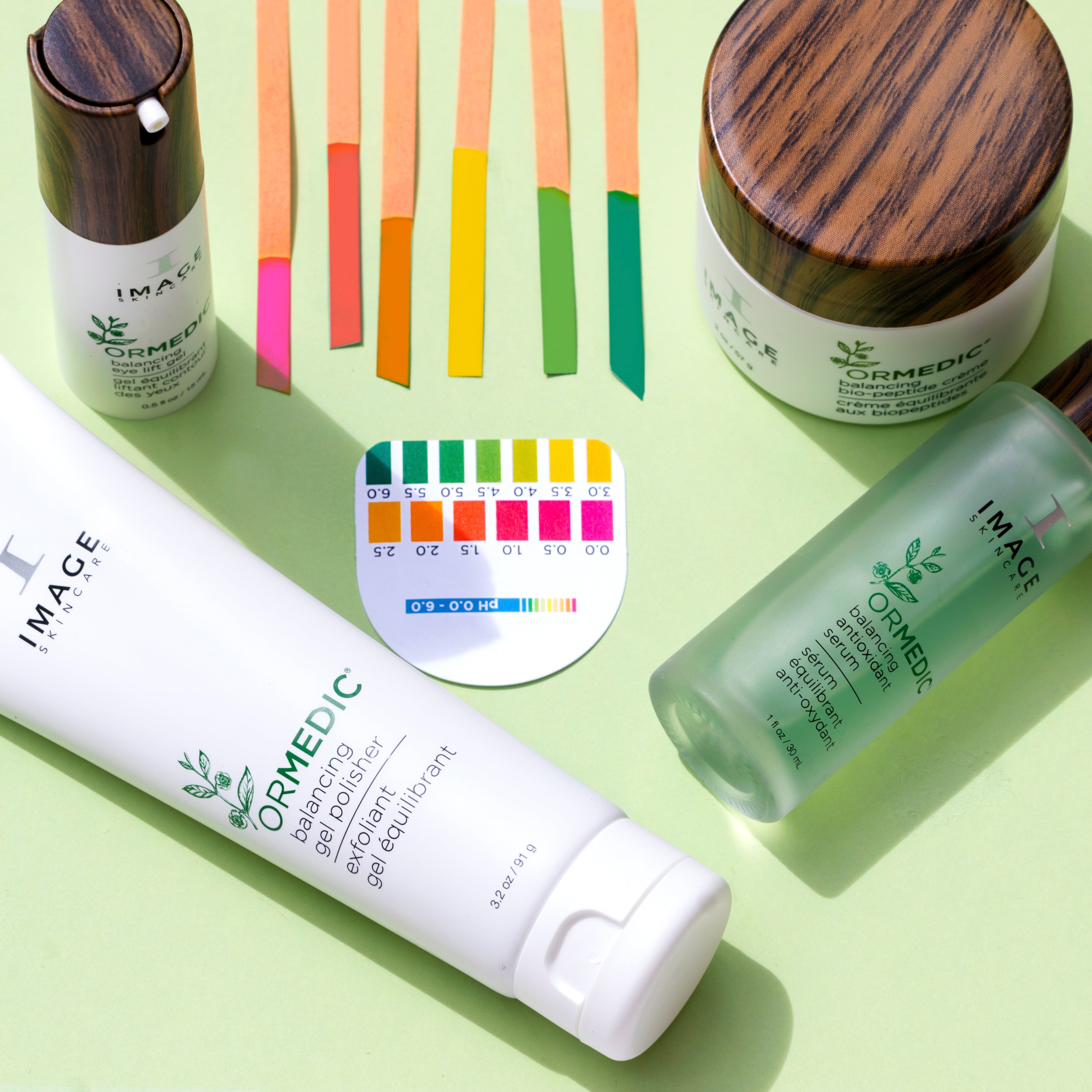 Skincare products including a tube, bottle, and jar on a green background with pH test strips.