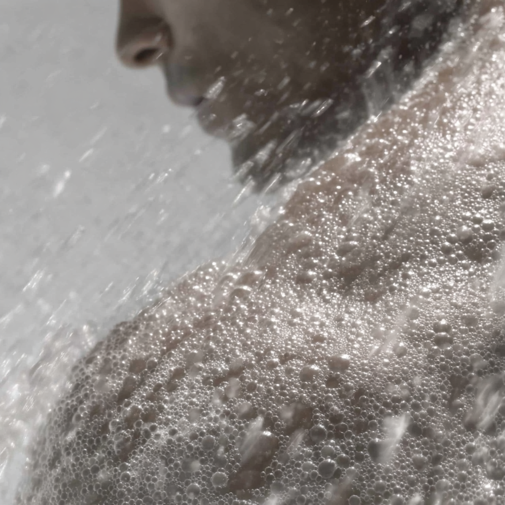 Person under a shower with water and soap bubbles