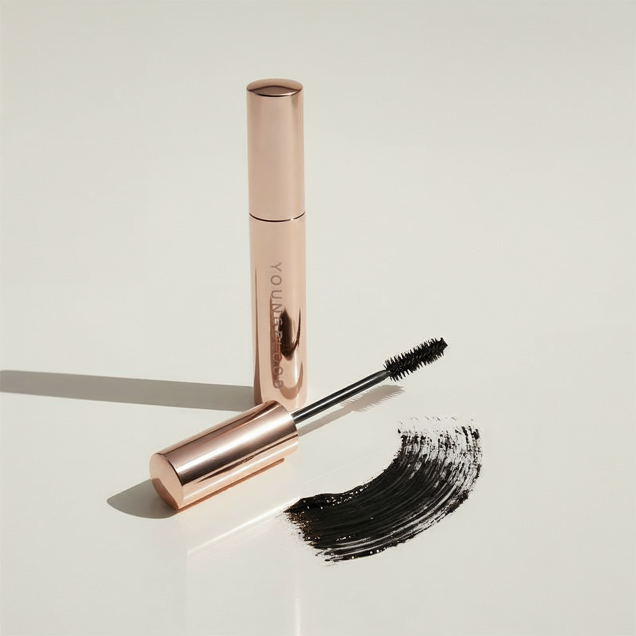 Youngblood's Rose gold Til Midnight mascara with black wand on a light beige background